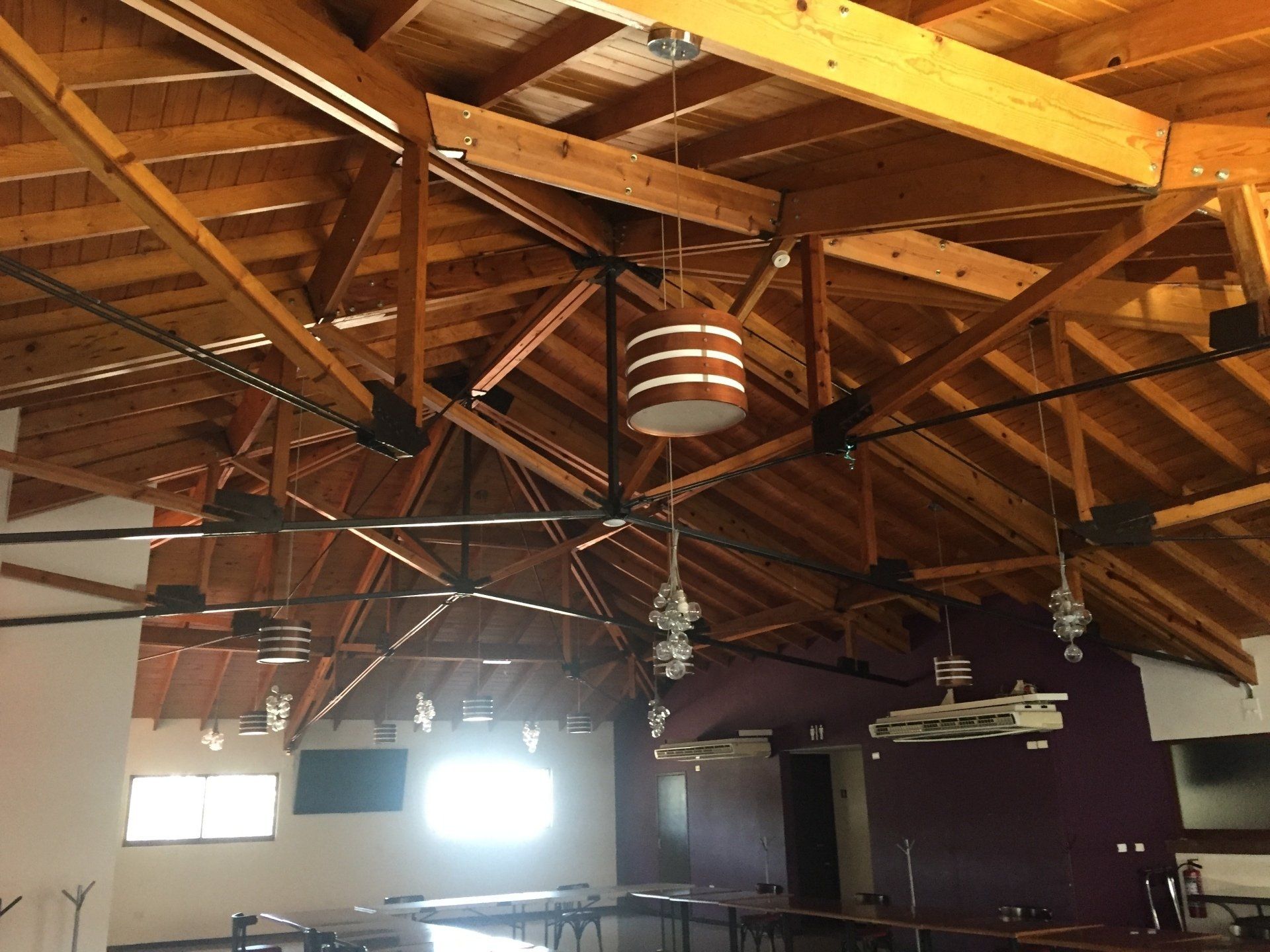 Techo con vigas de madera y grandes ventiladores de techo en un vestíbulo interior de estilo rústico.