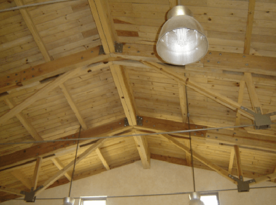 Techo abovedado de madera con vigas a la vista y una lámpara colgante de estilo industrial.