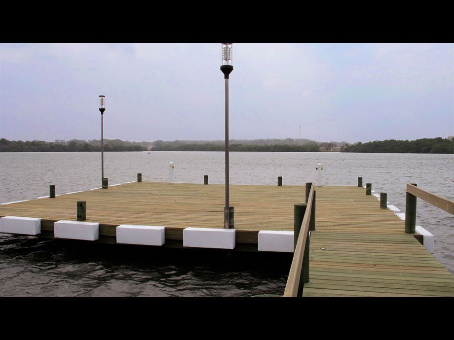 Muelle de madera que se adentra en un lago tranquilo bajo un cielo nublado.