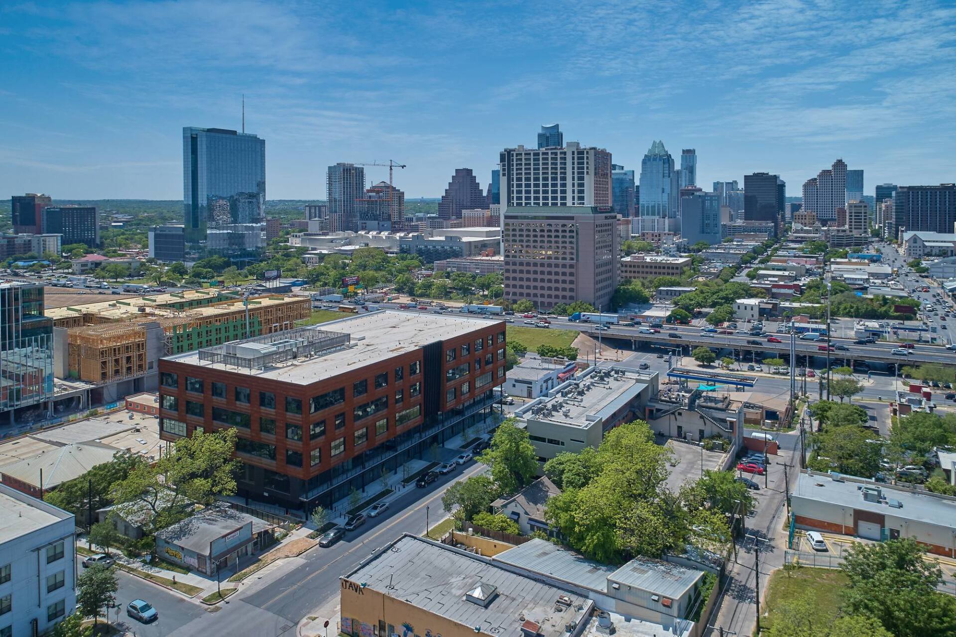 Aerial view of a city skyline under a clear blue sky, with modern buildings and construction cranes visible.