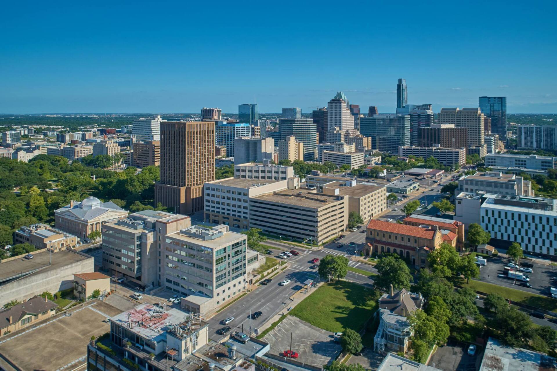 Aerial view of downtown Austin, Texas with modern skyscrapers and green spaces under a clear blue sky.