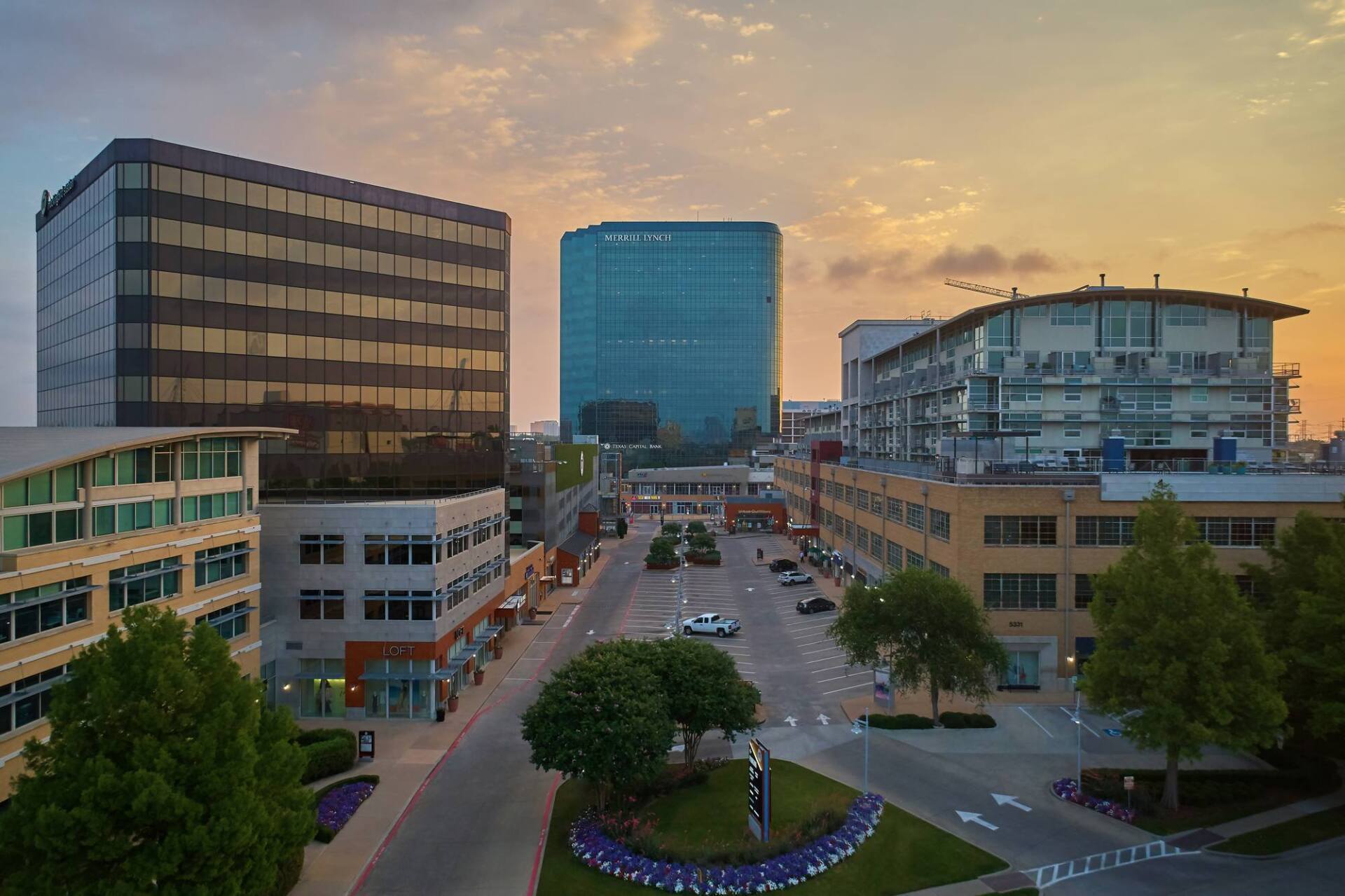 City street with tall buildings and a sunset sky.