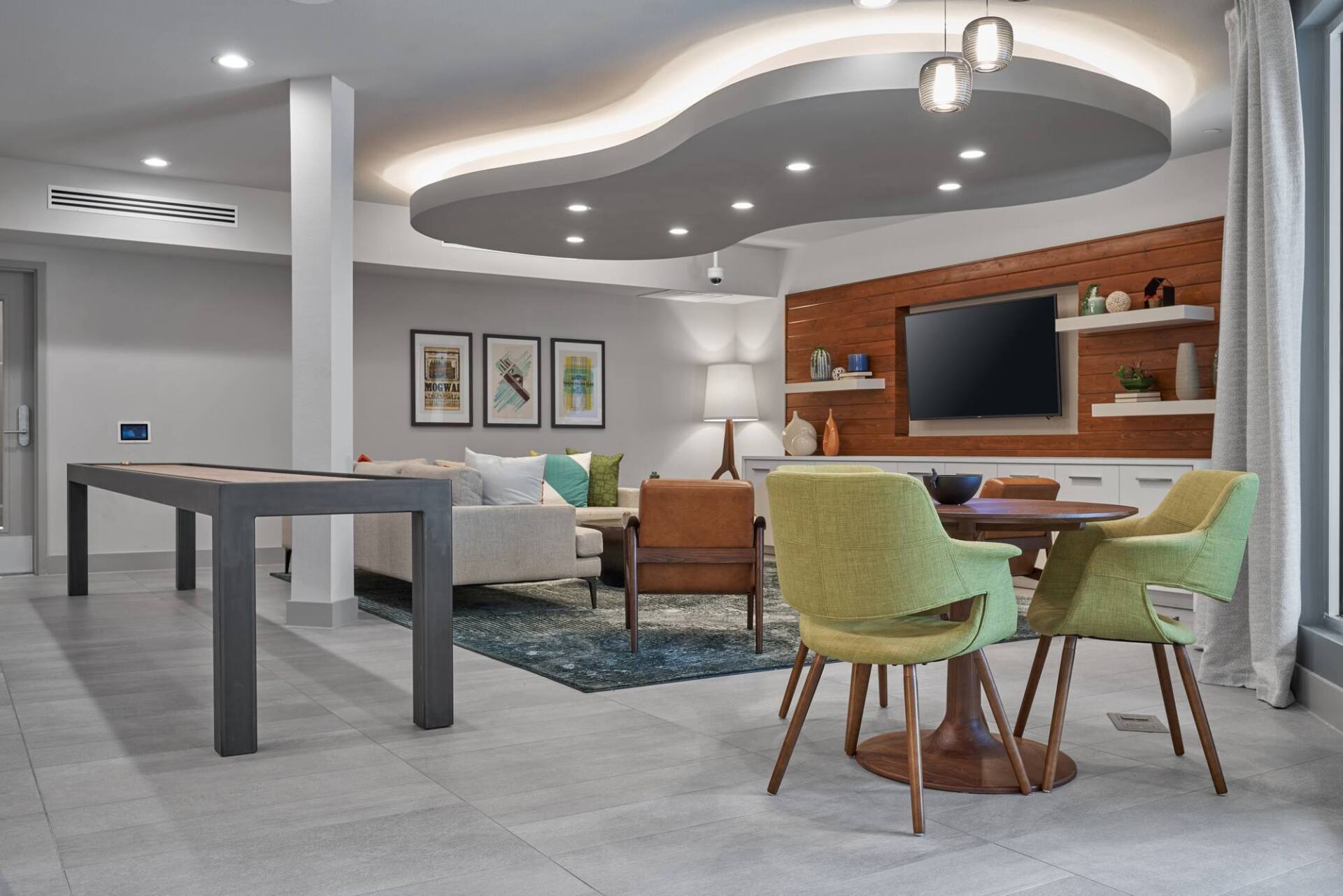 Modern living room with seating, dining, and a pool table under a unique ceiling design.