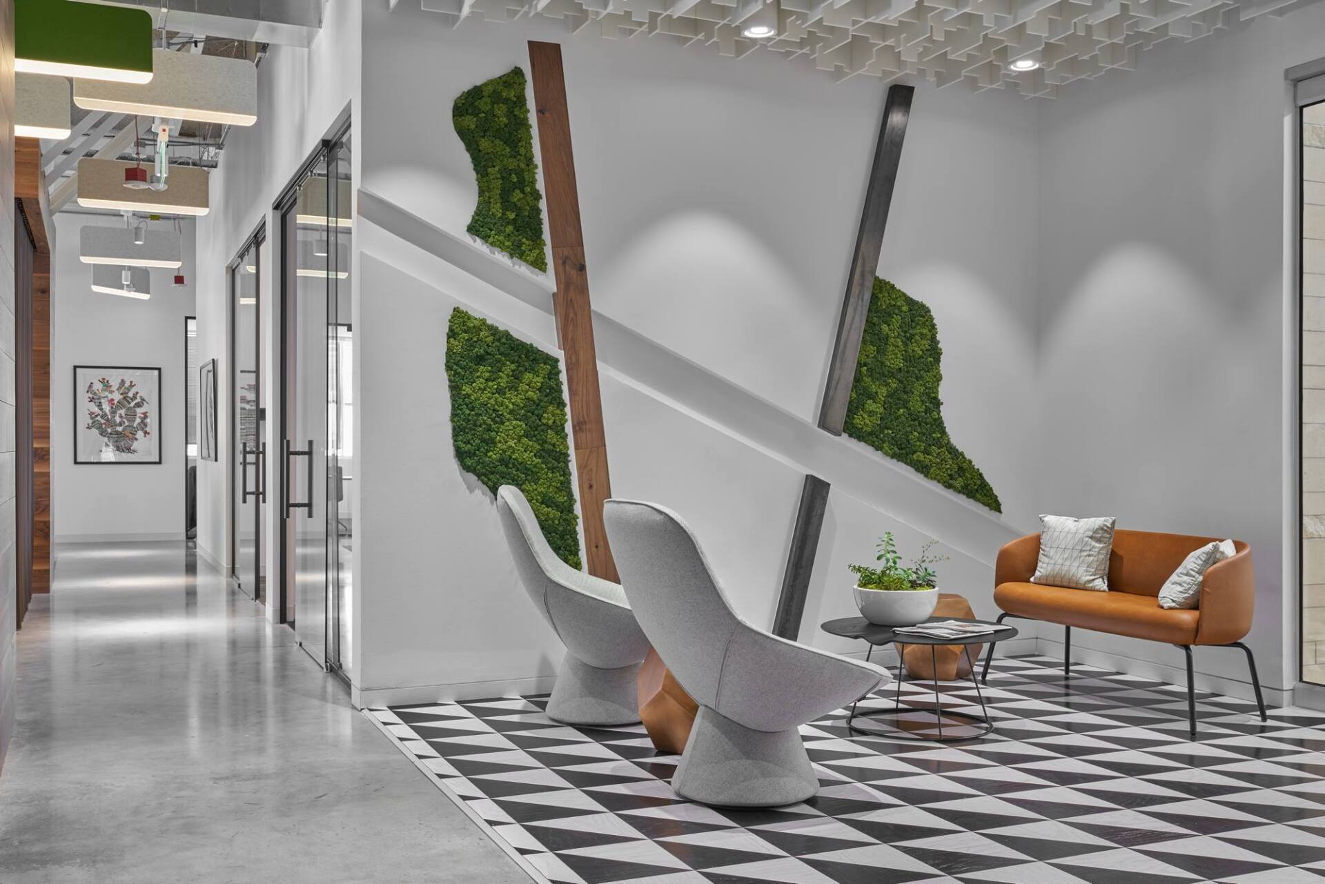 Modern office waiting area with chairs, sofa, and green wall art. Black and white geometric rug.