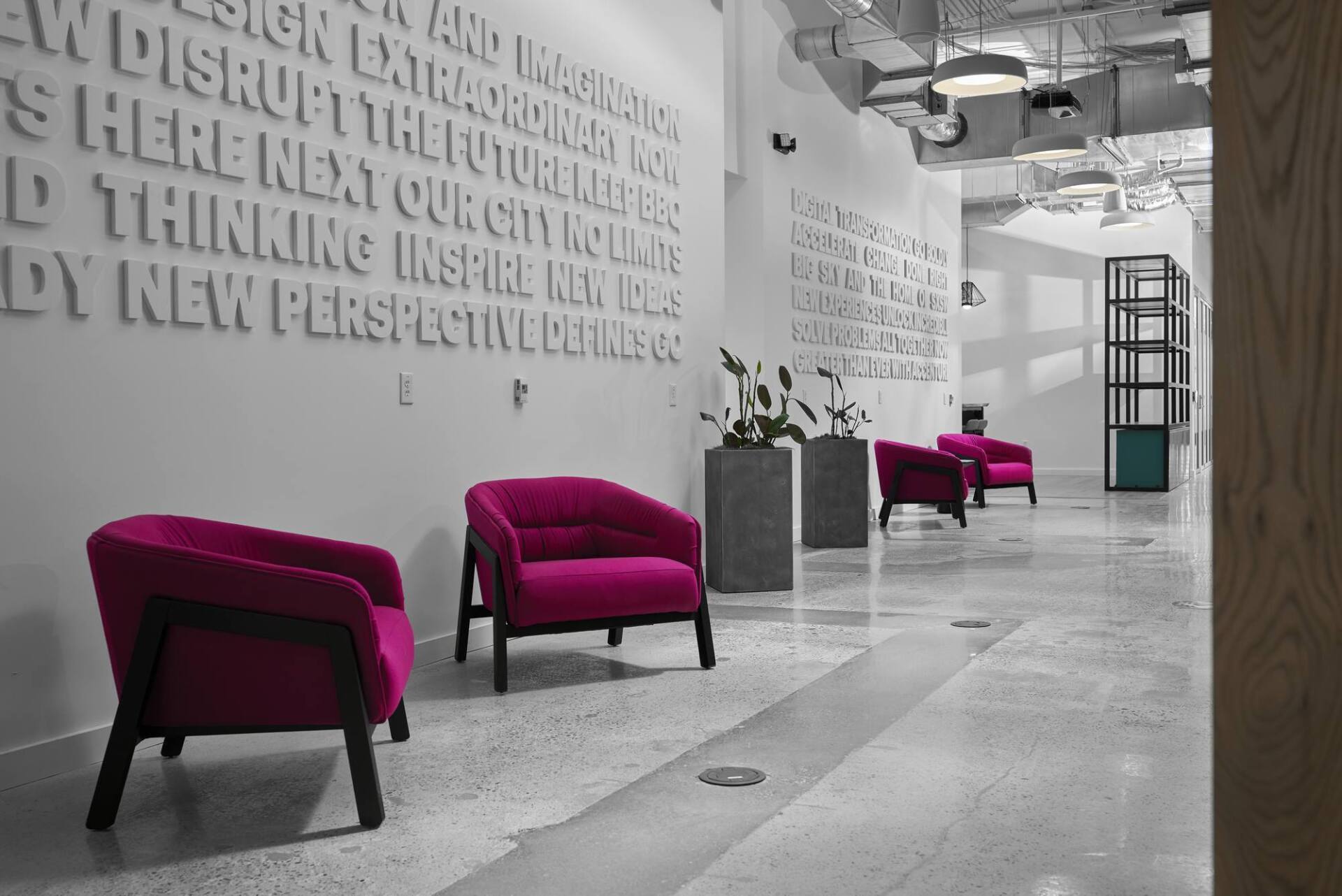 Modern waiting area with magenta armchairs and text on the white wall.