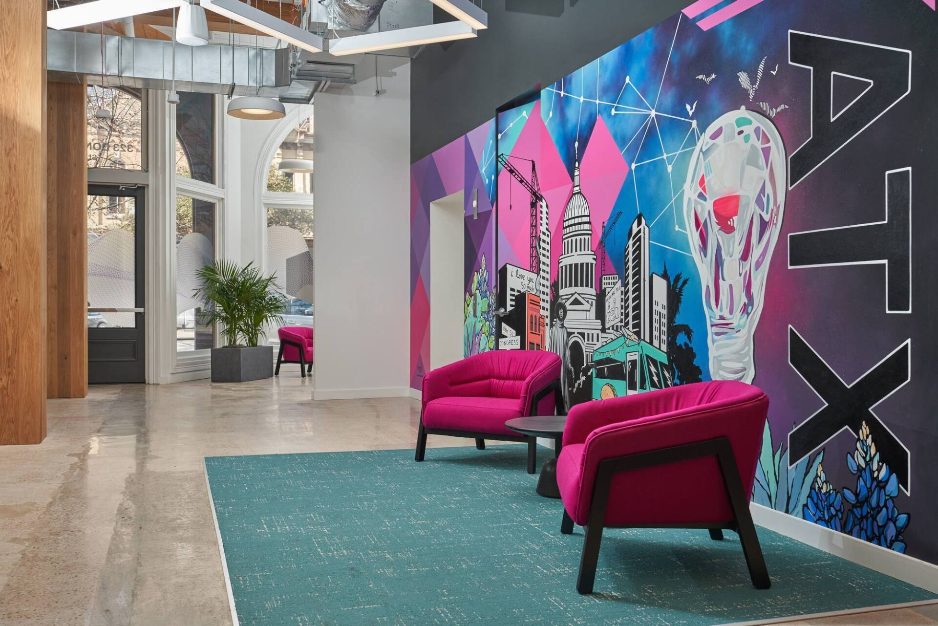 Lobby with magenta chairs, teal rug, and a colorful mural with