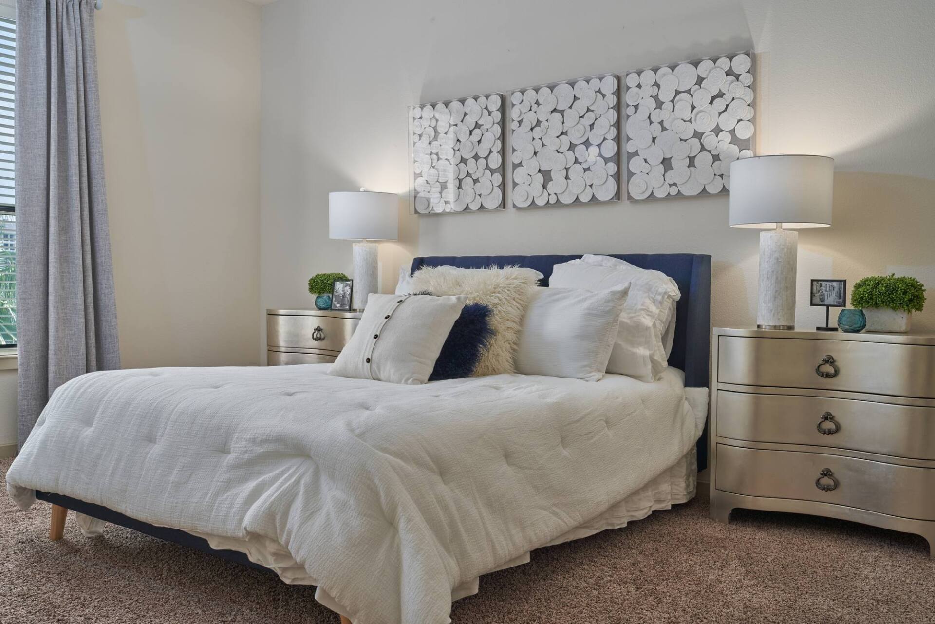 Bedroom with a blue headboard, white bedding, and two nightstands with lamps.