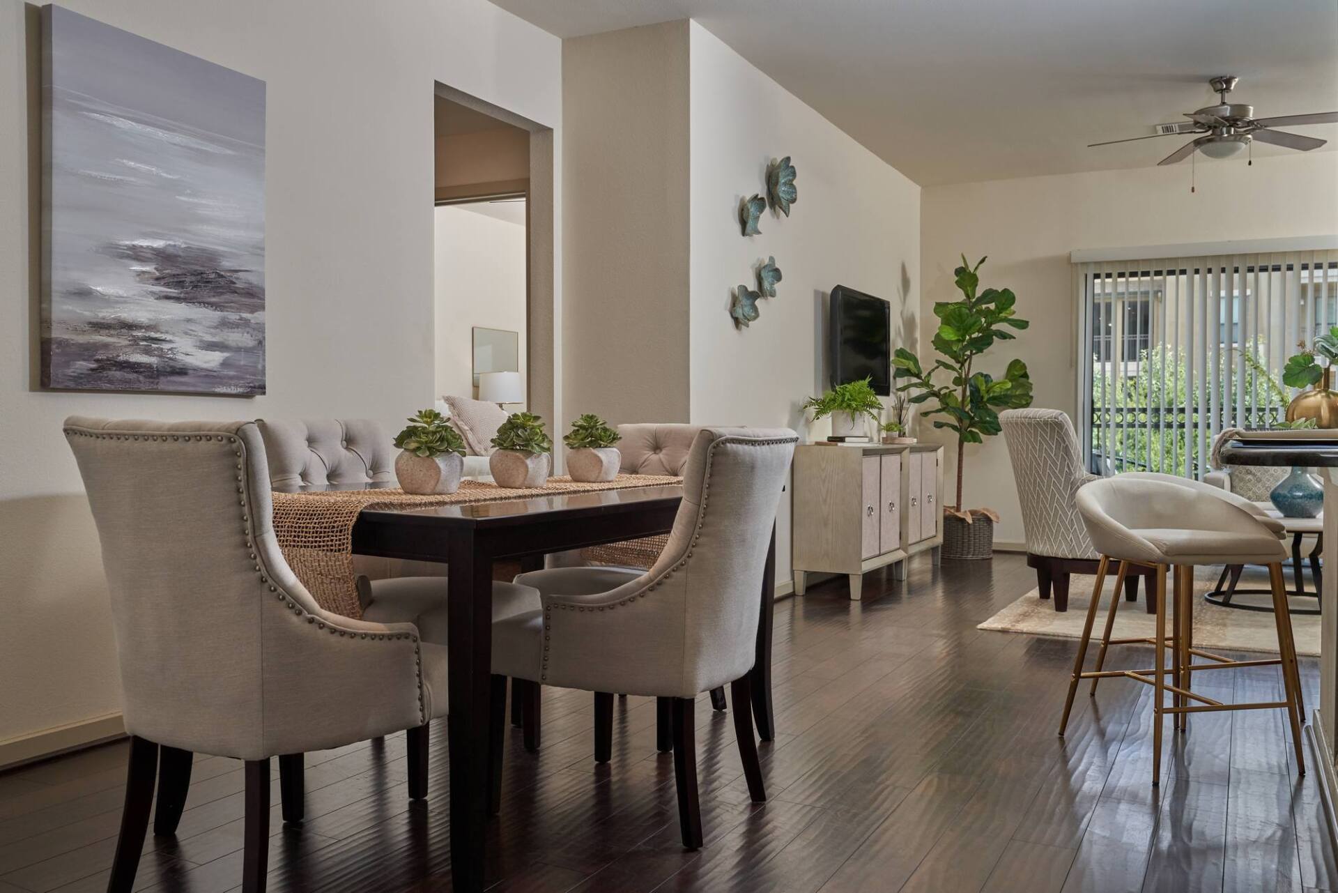 Dining area with dark wood floors, table set for six, and access to a balcony.