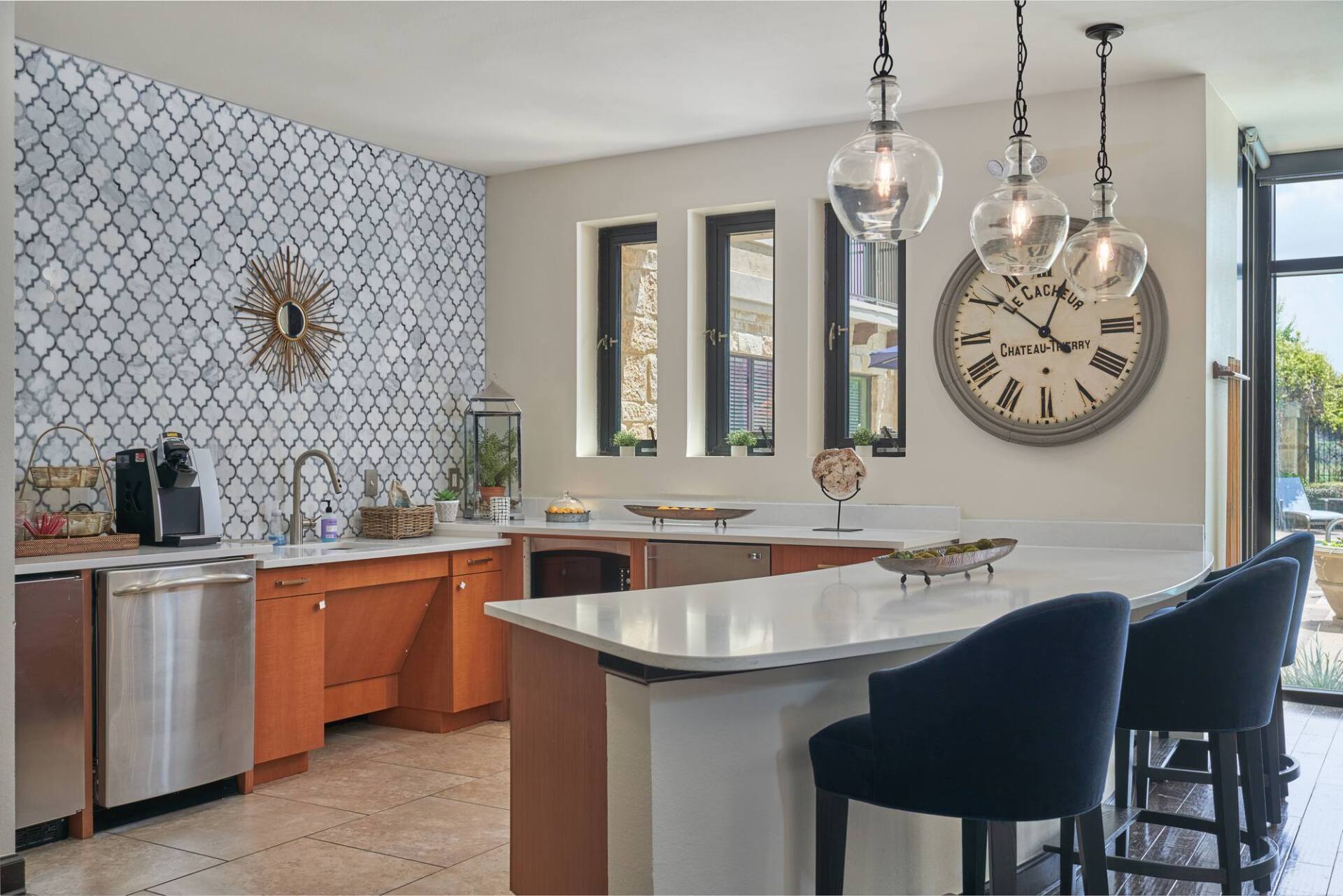 Kitchen with orange cabinets, white countertops, blue tile backsplash, and blue bar stools.