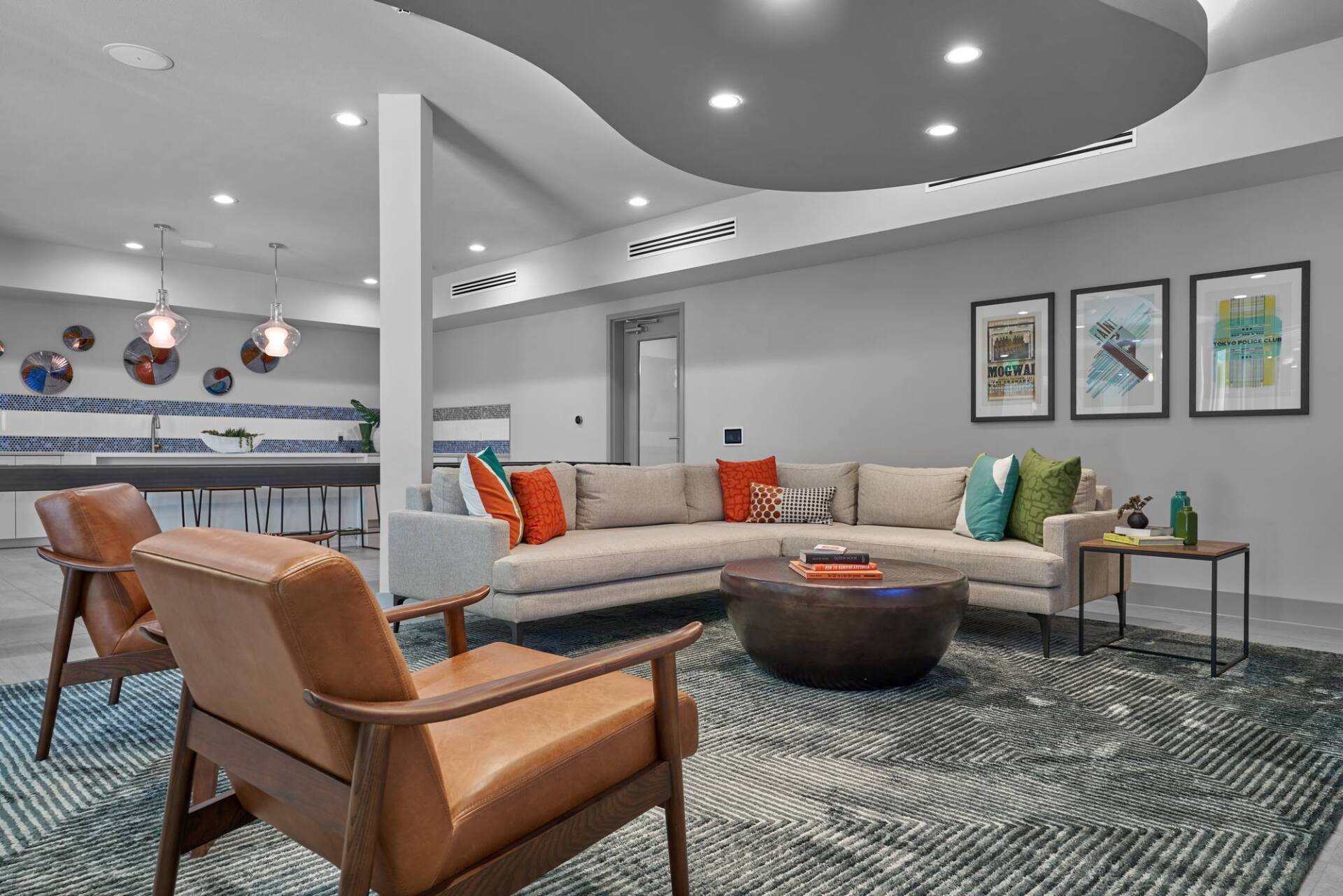 Modern lounge area with sectional sofa, armchairs, rug, and artwork.