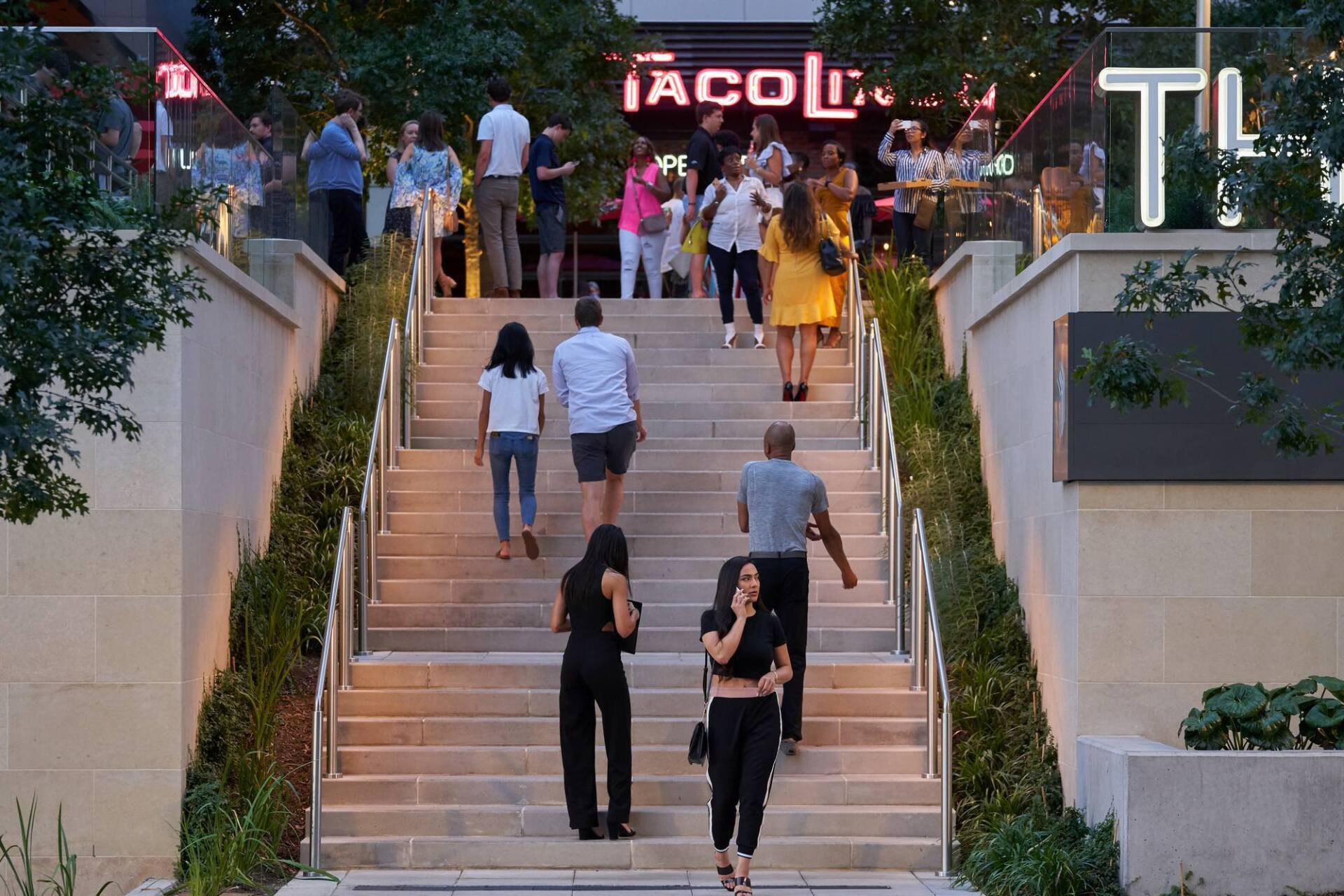 People walking up and down outdoor steps leading to a restaurant entrance with a 