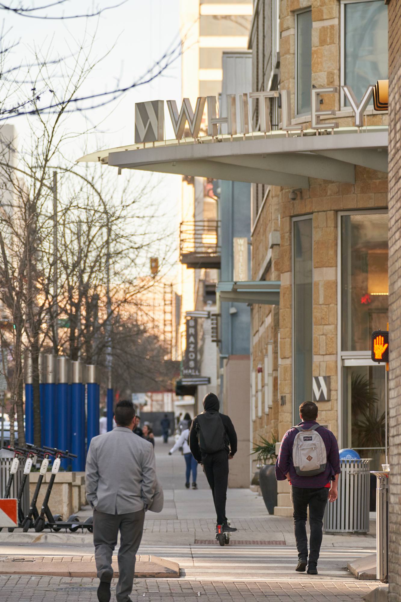 People walking on a city sidewalk. The building 