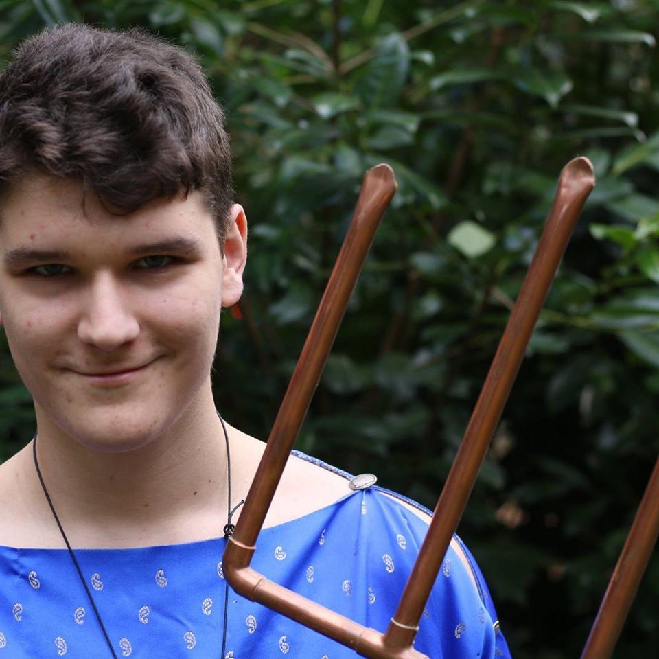 A young man in a blue shirt is holding a trident,  representing Poseidon. 
