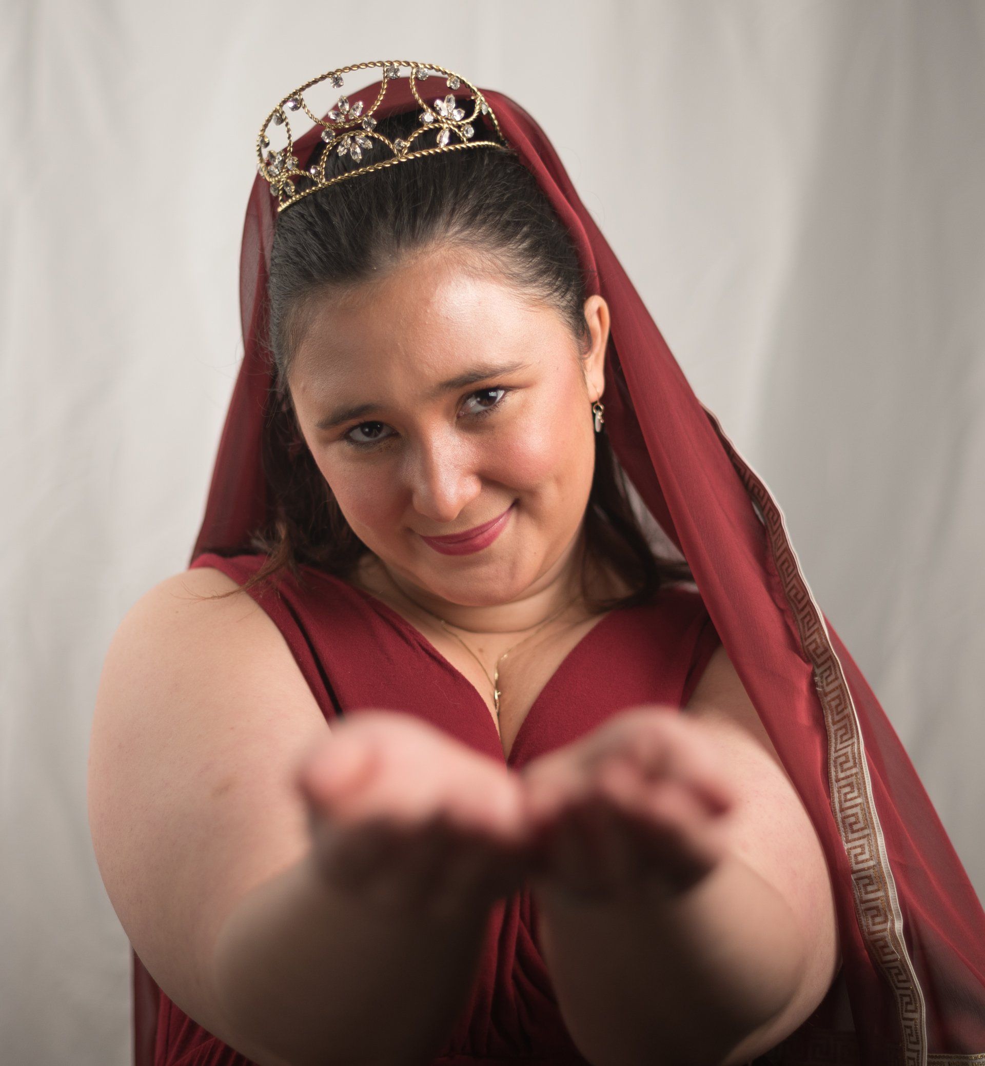 A woman wearing a red dress and a tiara on her head,  representing Hestia.