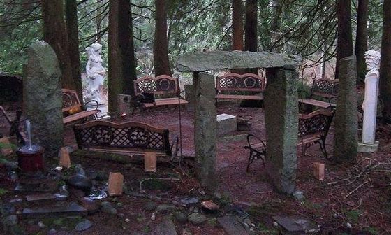 A group of stone benches are sitting in the middle of a forest henge.