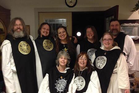 A group of people are posing for a picture in a room, members of the Aquarian Tabernacle Church.