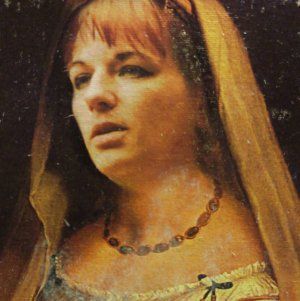 A close up of a woman wearing a veil and a necklace,  representing Demeter.