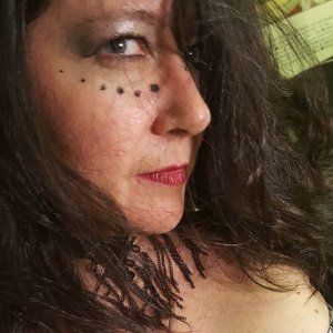 A close up of a woman 's face with long hair and red lips, representing Hekate.