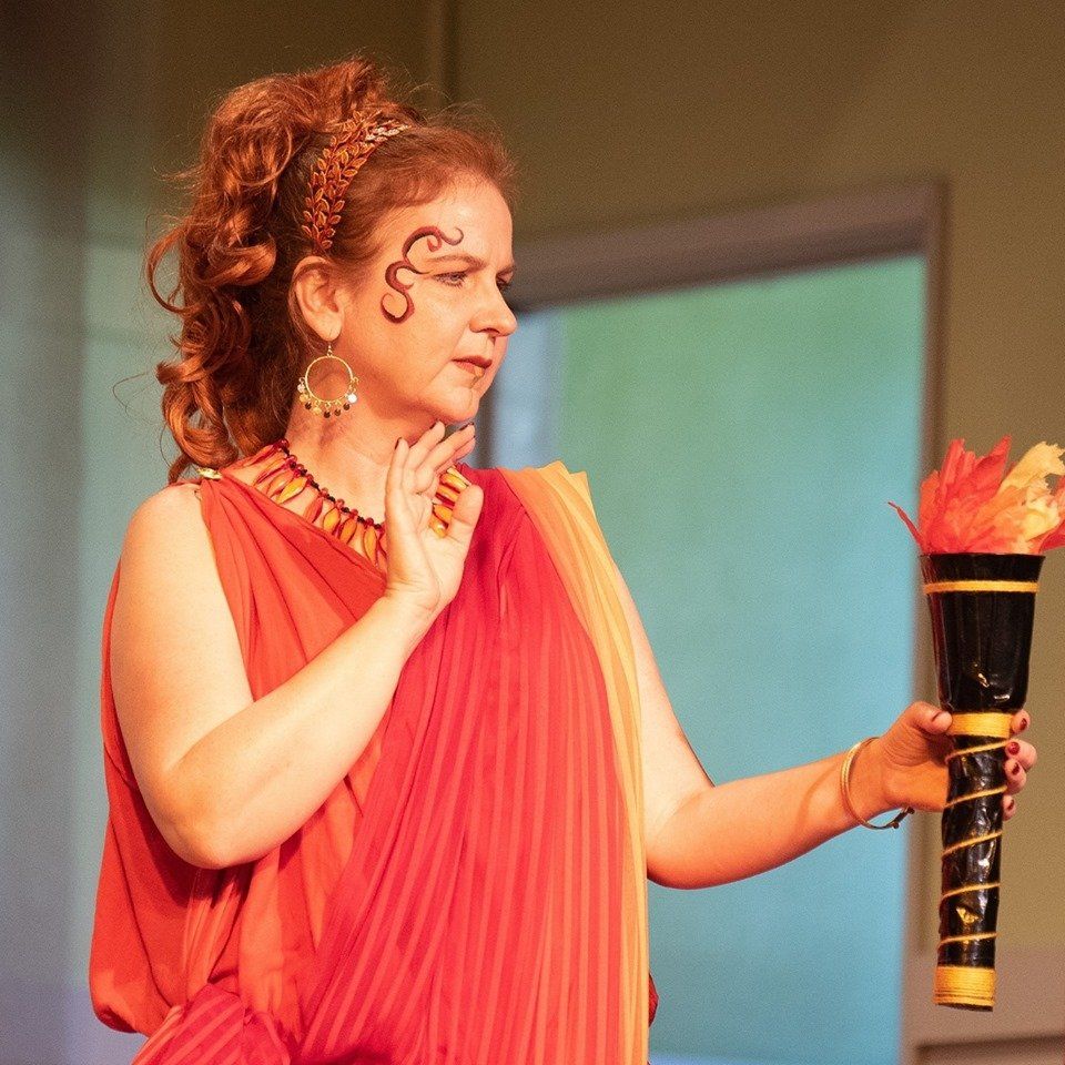 A woman in a red dress is holding a torch,  representing Hestia.