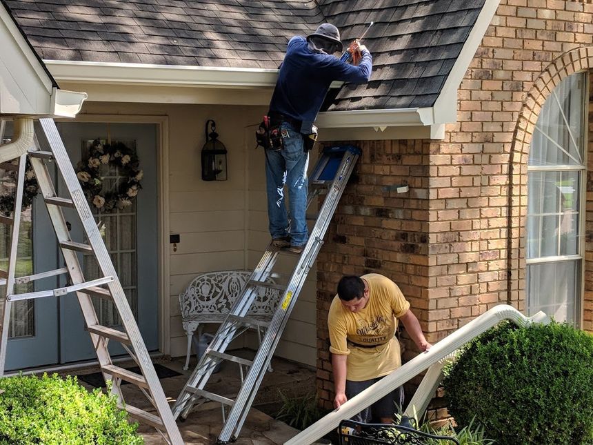 Two men are working on the roof of a house.