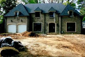 A large house is being built in the middle of a dirt field.