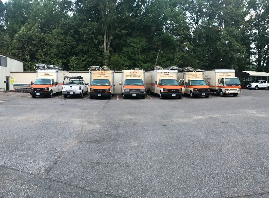 A row of moving trucks are parked in a parking lot