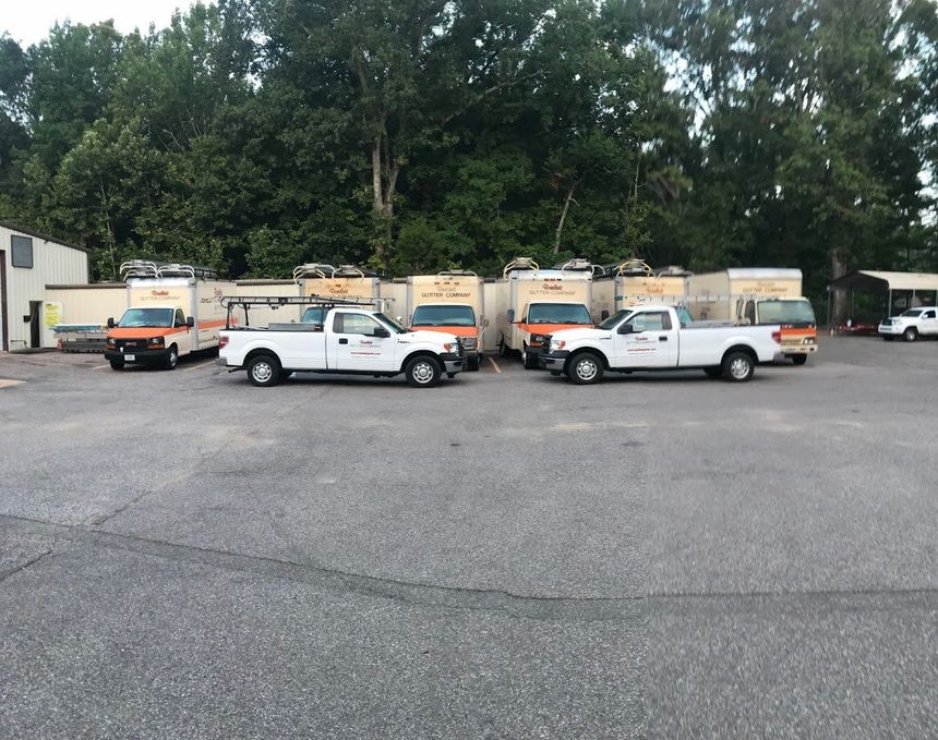 A row of white trucks are parked in a parking lot.