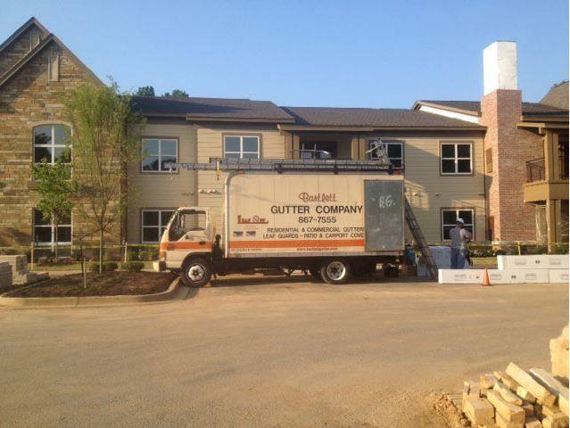 A gutter company truck is parked in front of a building