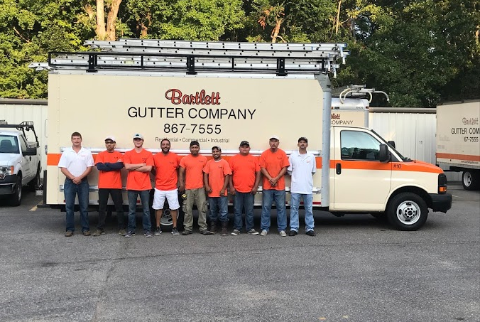 A group of men are standing in front of a gutter company truck.