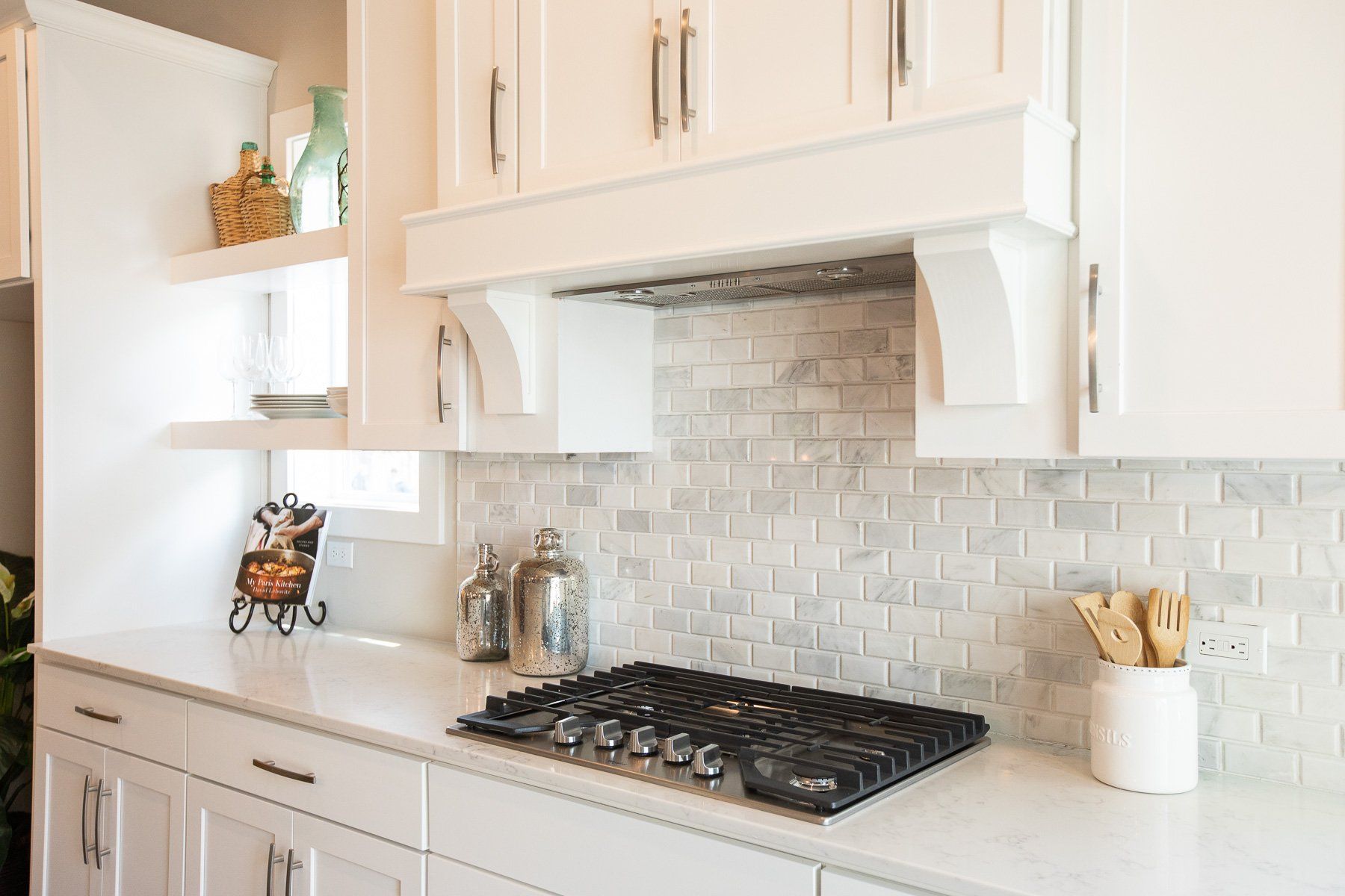 A kitchen with white cabinets and a stove top oven.
