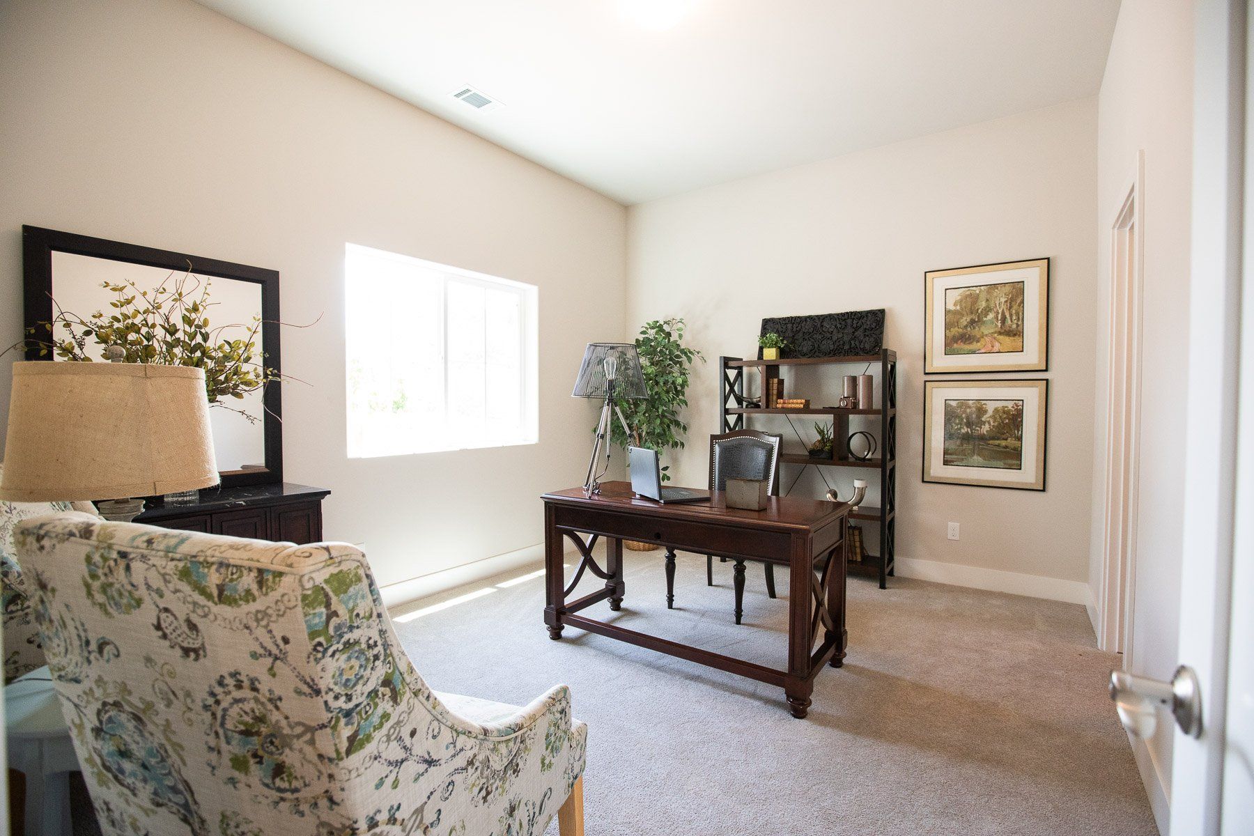 A home office with a desk , chair , lamp and mirror.