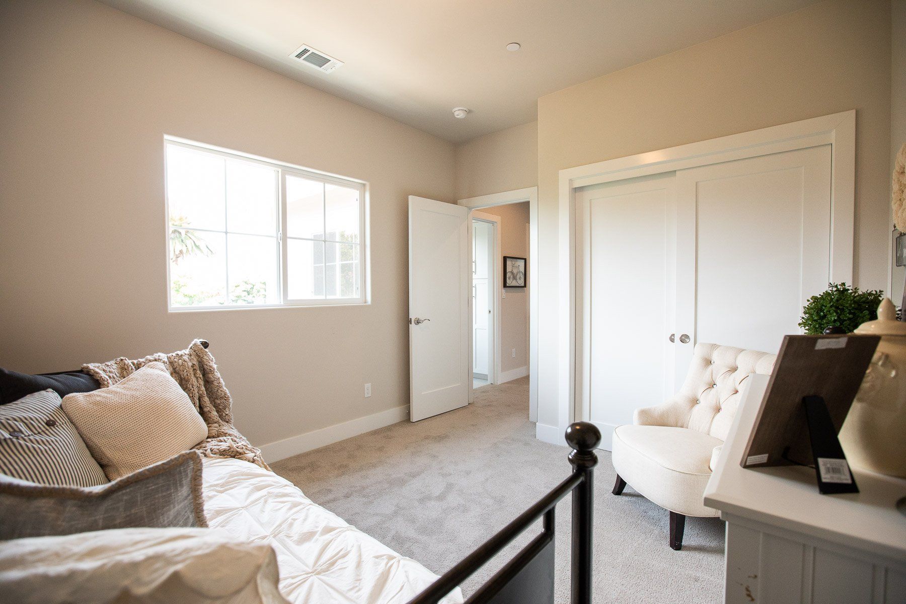 A bedroom with a bed , chair , dresser and window.