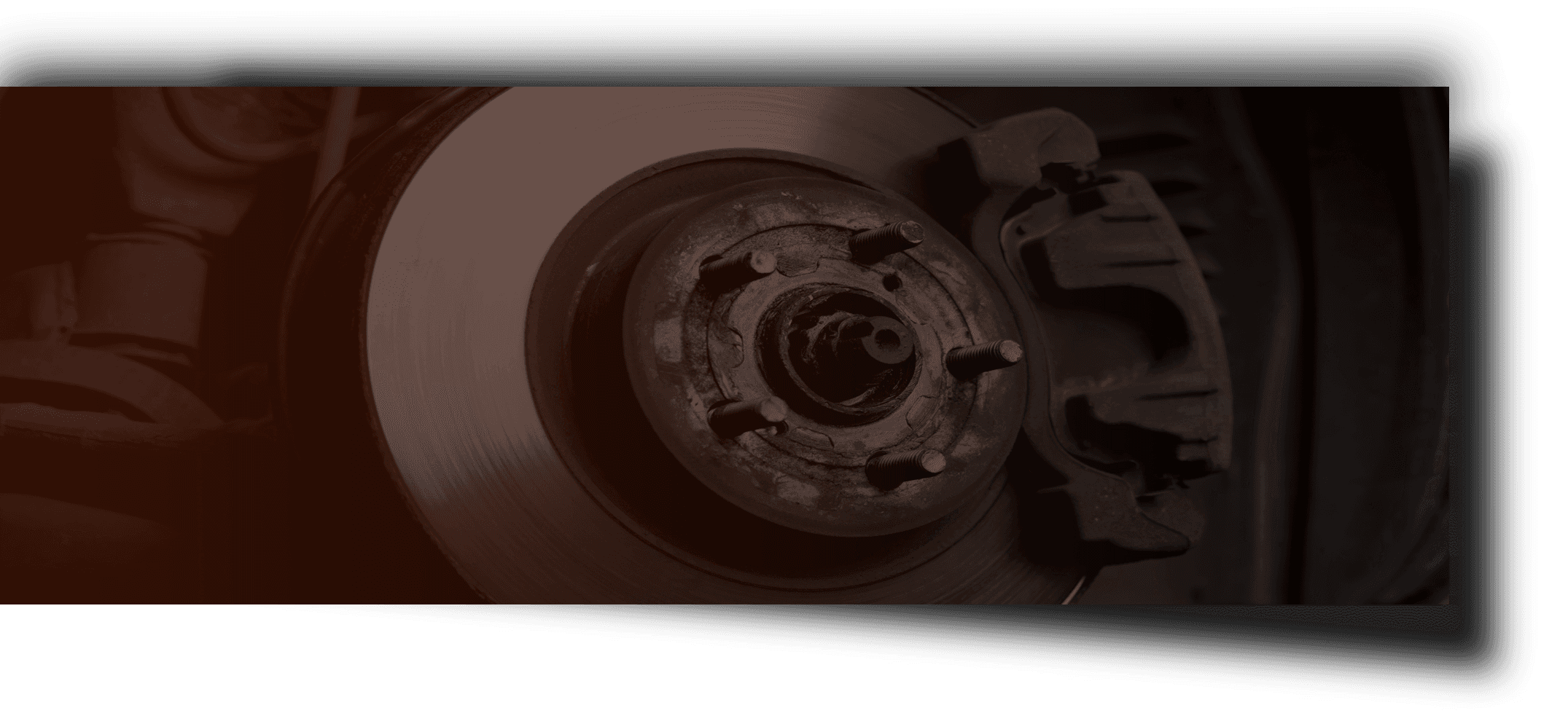 Close-up of a dark red car wheel rim and tire in shadow