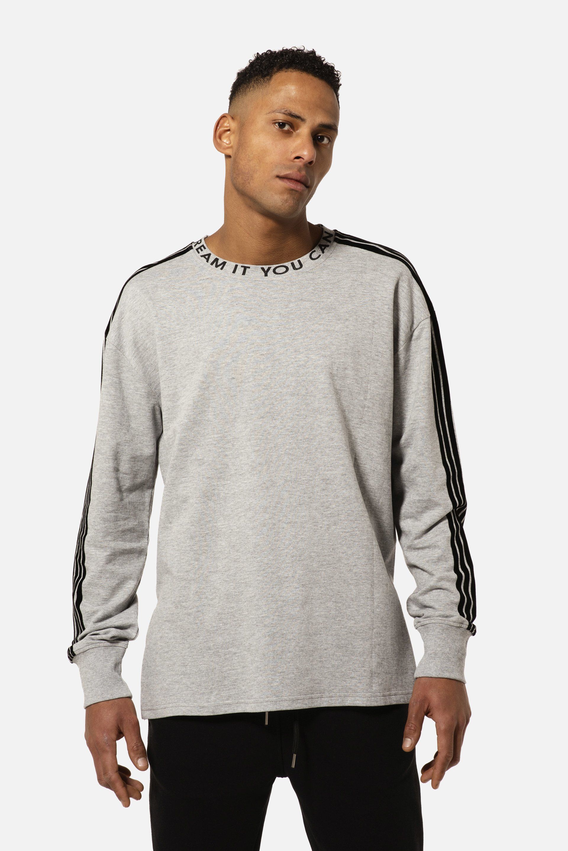 Un uomo che indossa un maglione grigio con strisce nere sulle maniche