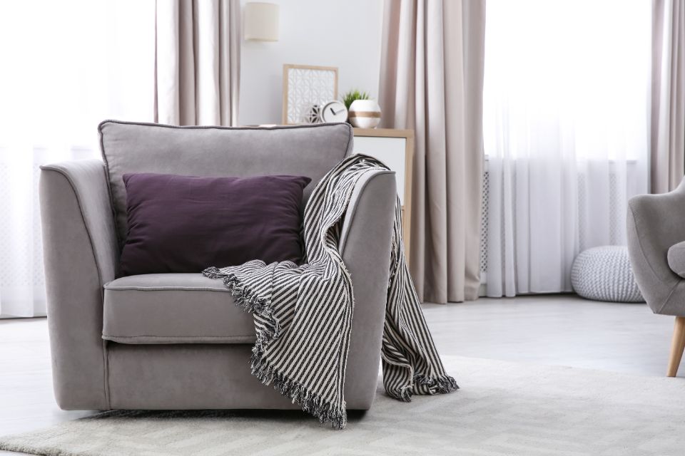 salotto con tende color champagne e poltrona grigia