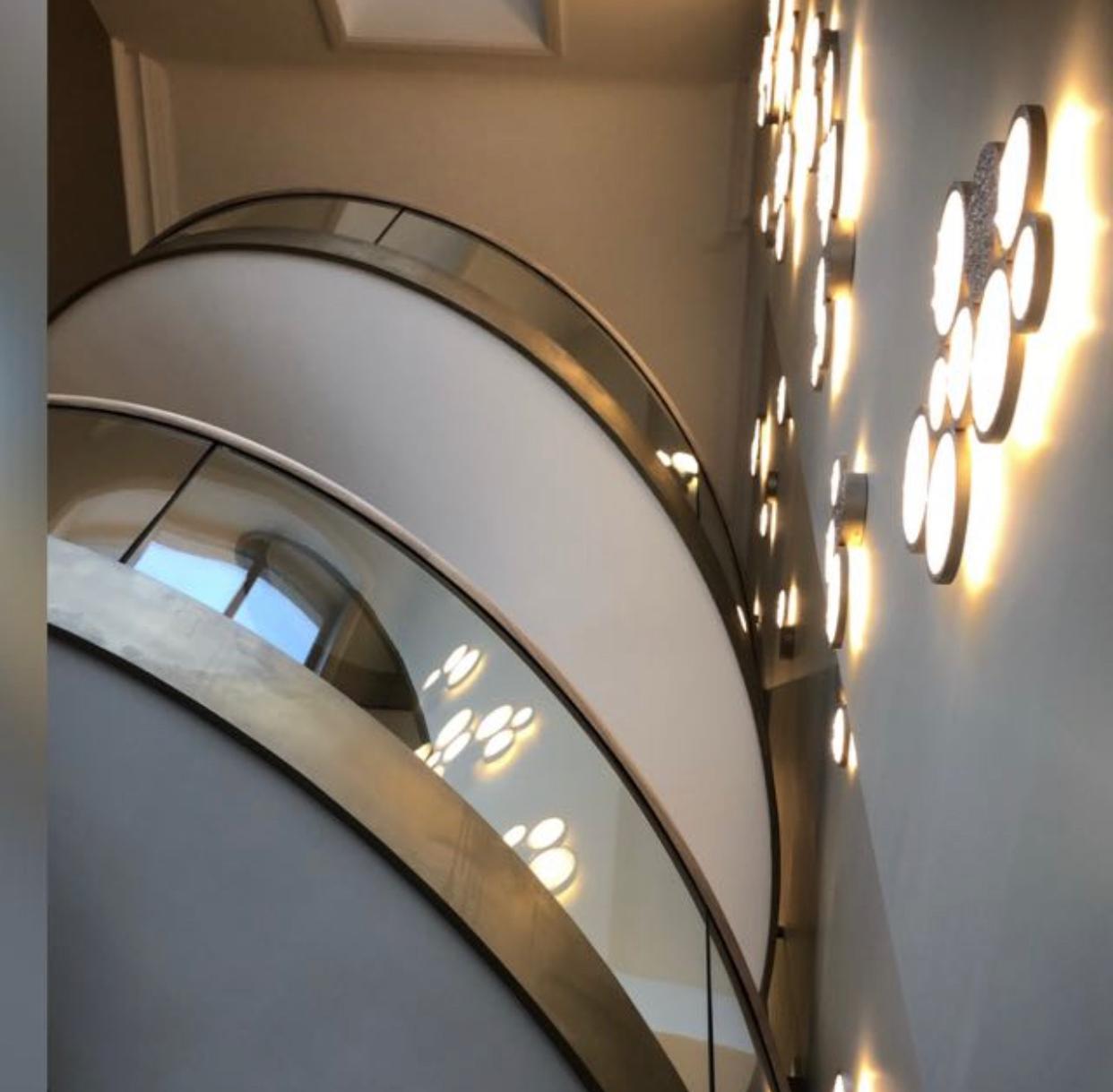 A spiral staircase with a glass railing and lights on the wall