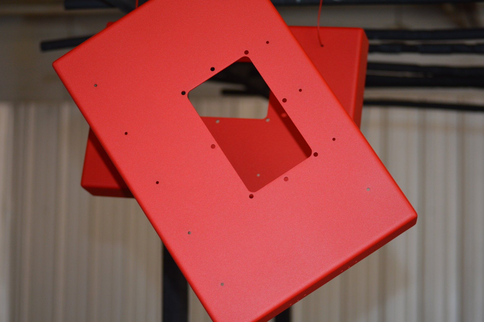Two red boxes with holes in them are hanging from the ceiling.