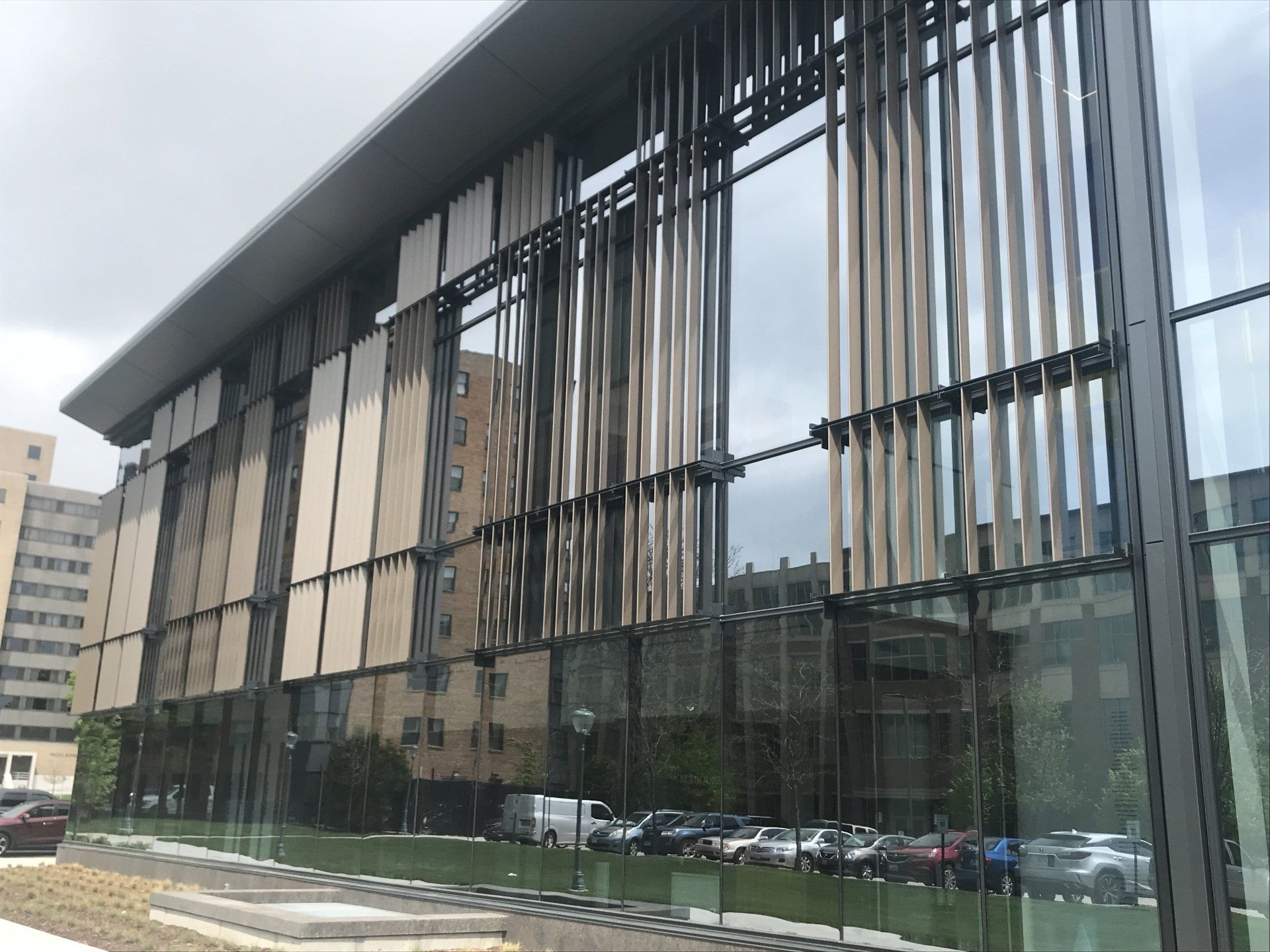 A large building with a lot of windows and a lot of cars parked in front of it.