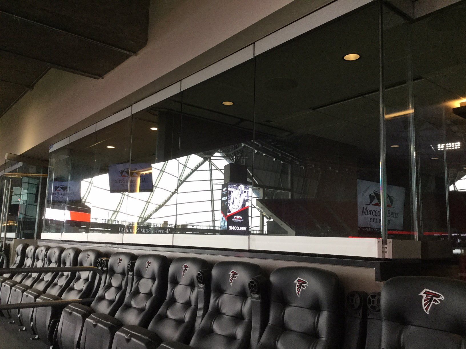 A row of black seats in a stadium with a large window.