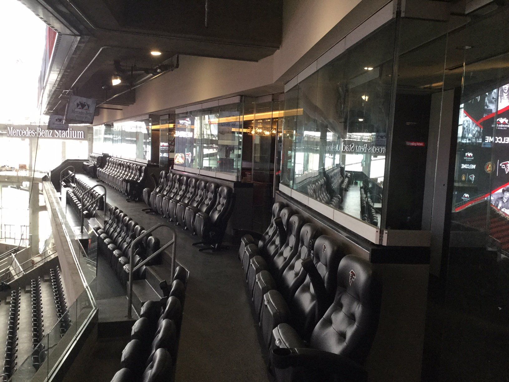 A row of empty seats in a stadium with a large screen on the wall.