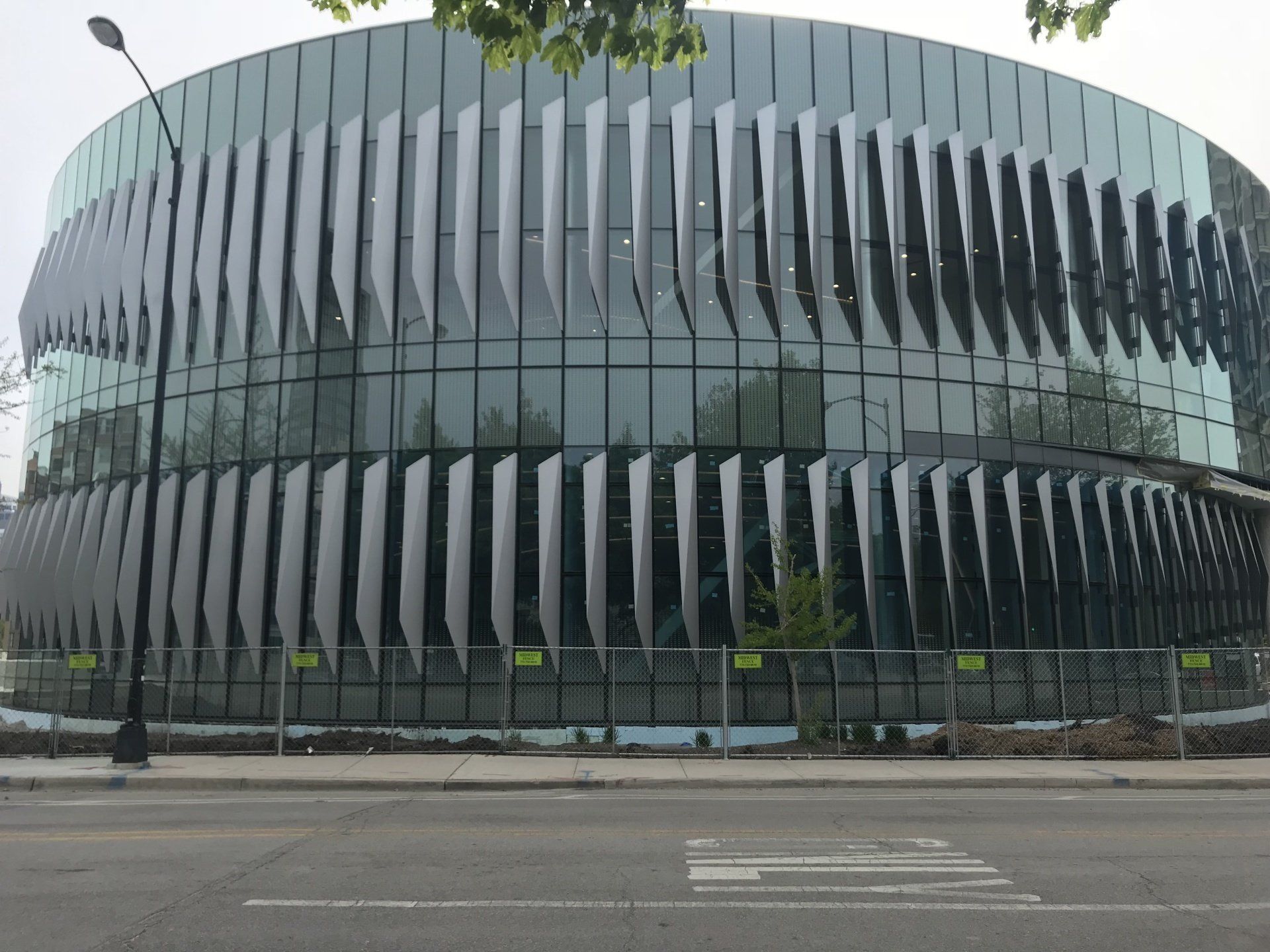 A large building with a lot of windows is sitting on the side of the road.