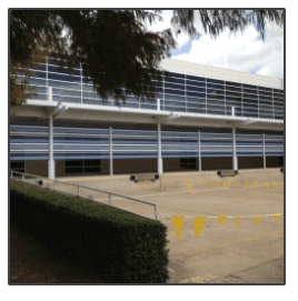 A large building with a lot of windows and a parking lot in front of it