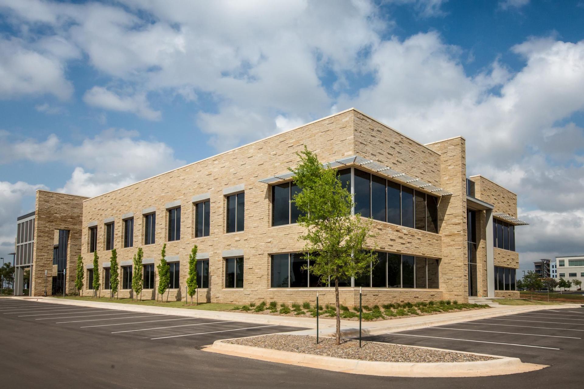 A large brick building with a lot of windows and trees in front of it.
