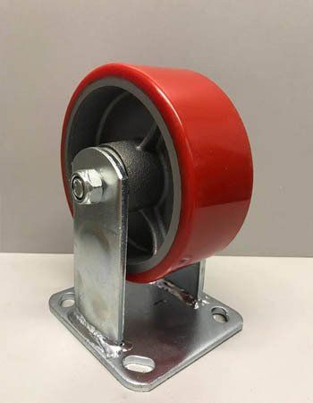 Una rueda roja está colocada encima de un soporte de metal sobre una mesa.