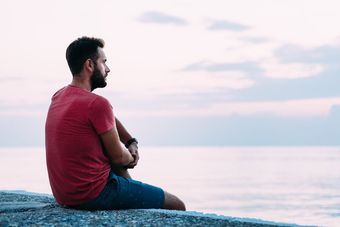 man sitting by ocean