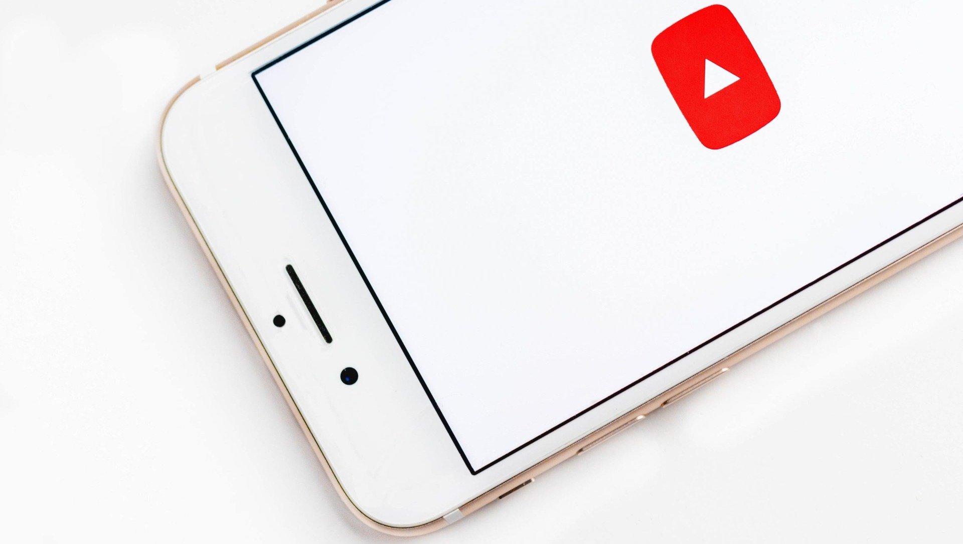 Un teléfono inteligente blanco que muestra el ícono de reproducción de YouTube en una pantalla en blanco.