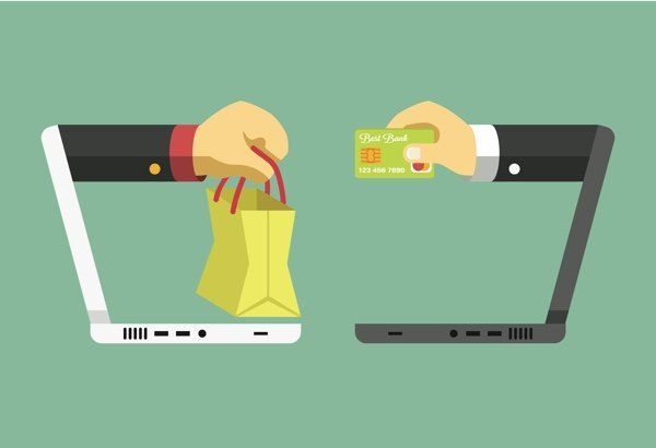 Manos intercambiando una bolsa de compras y una tarjeta de crédito entre dos computadoras portátiles sobre un fondo verde.