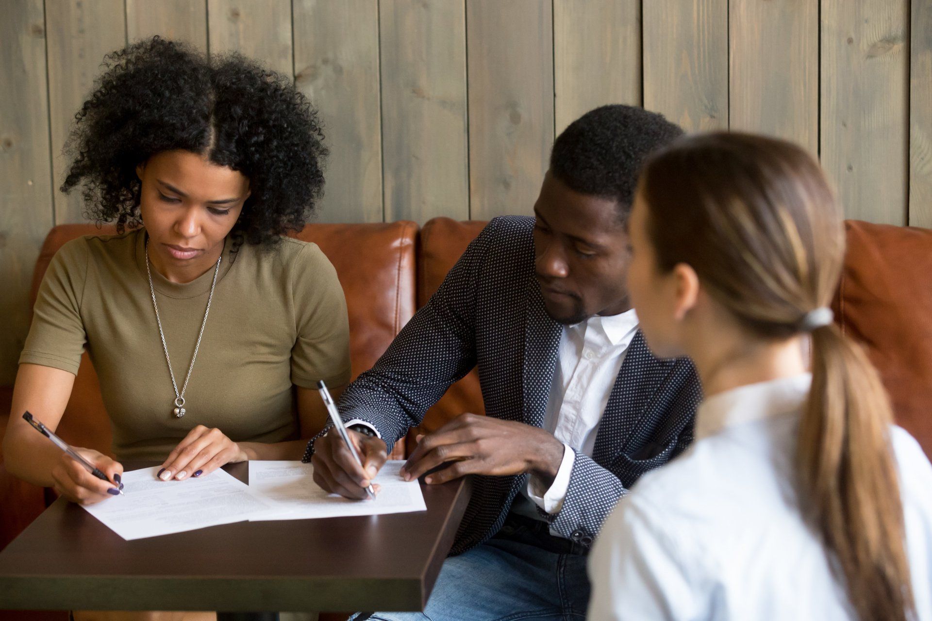 A man and a woman are sitting at a table signing a document.