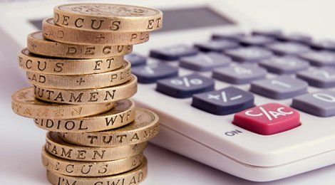 A pile of £1 coins beside a calculator