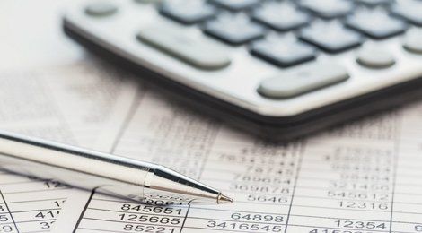 A silver pen and a calculator on a sheet of figures